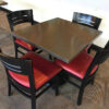 breakroom table with granite top and four chair with black frames and back and red cushions