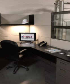 dark gray workstation with white wall, window and black chair.