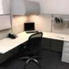 white workstation with overhead drawer, black phone and black chair