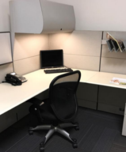 white workstation with overhead drawer, black phone and black chair